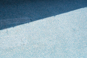 Abstract geometric study of blue mosaic tiles divided by a sharp diagonal shadow line.