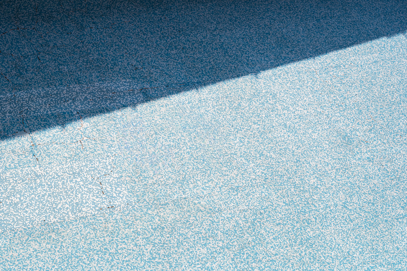 Abstract geometric study of blue mosaic tiles divided by a sharp diagonal shadow line.